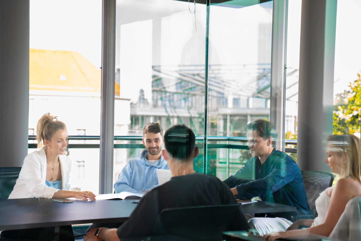 Fünf Personen sitzen um einen Konferenztisch herum und sind in eine Besprechung vertieft