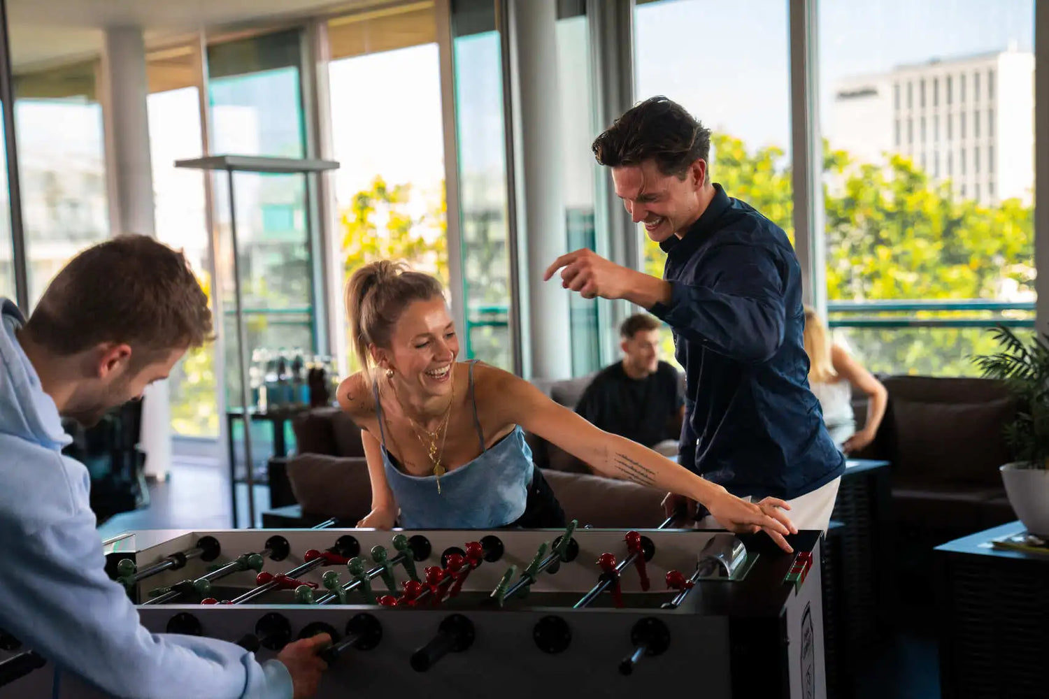 Drei Personen spielen zusammen Tischfußball